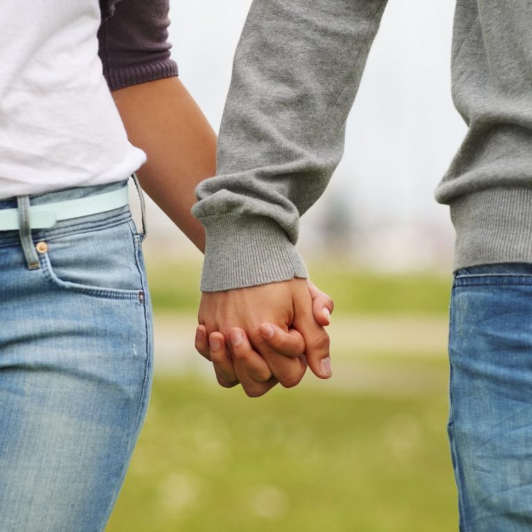 Paarberatung und Eheberatung am Niederrhein Zwei Personen halten Händchen in einer grünen Wiesenlandschaft.